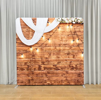 Rustic wood plank backdrop with white draping and warm string lights