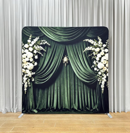 Emerald green draped backdrop with white floral arrangements and a chandelier